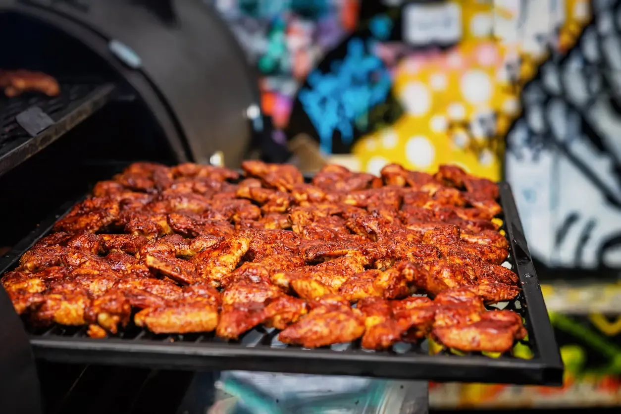 Crispy chicken wings in spicy marinade on a BBQ grill.