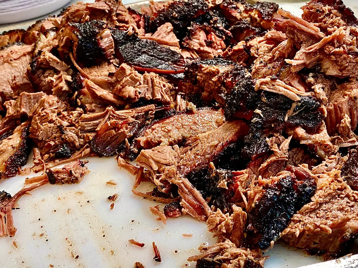 Whole beef brisket chopped on a cutting board. 