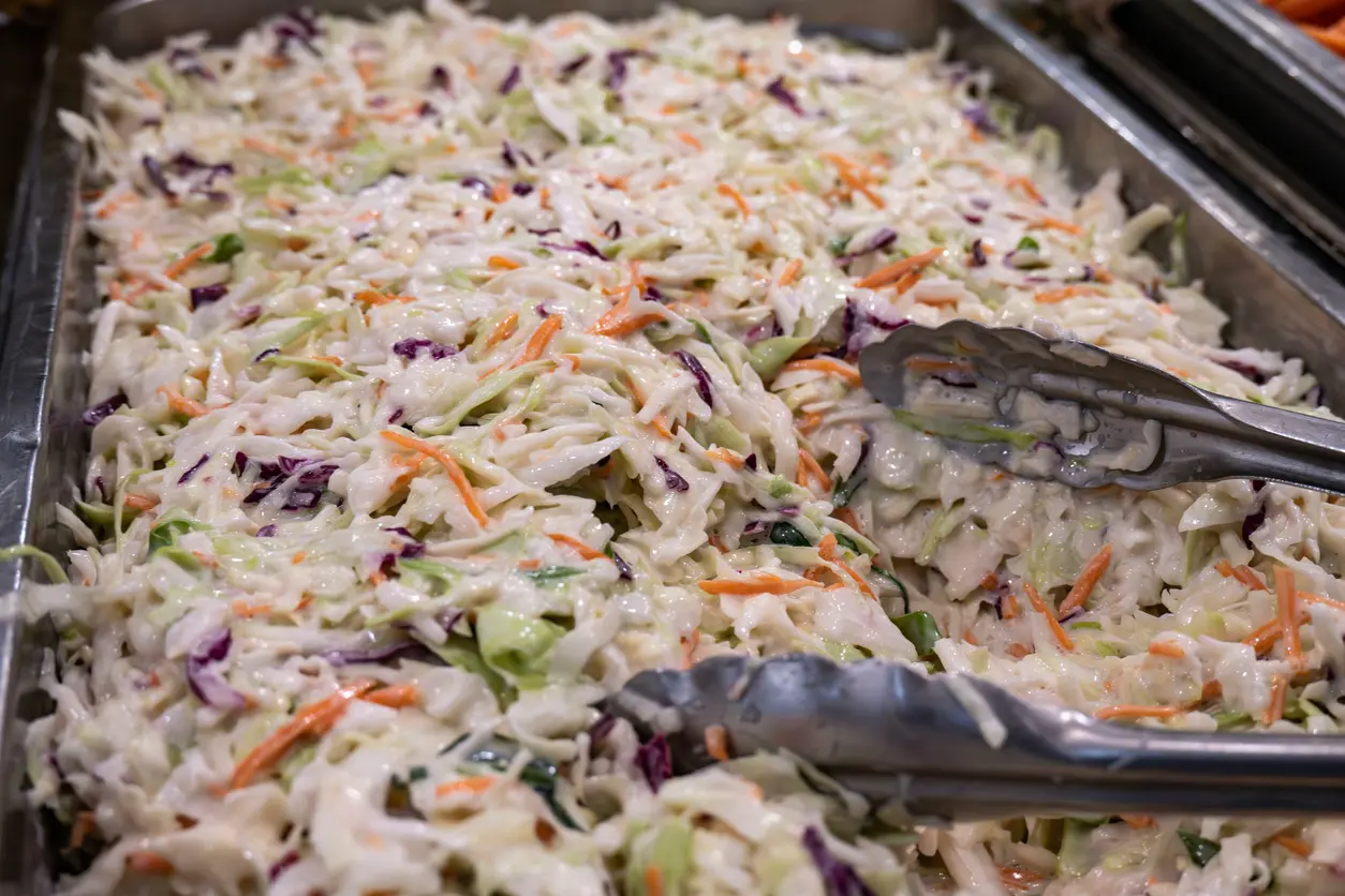 A pan of creamy and flavorful coleslaw in a catering container. 